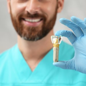 Smiling dental professional holding a dental implant model during a consultation with an implant dentist in Stuart