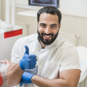 Smiling dentist giving a thumbs-up beside a patient in a modern dental clinic for cosmetic dentistry in Stuart