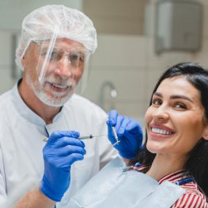 Cosmetic dentistry in Stuart — dental exam scene with a dentist holding tools beside a patient with a bright smile